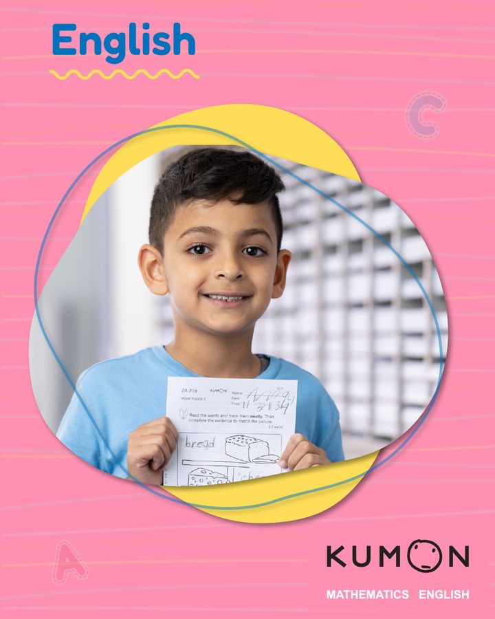 Kumon English. A boy smiles as he holds up a Kumon worksheet.